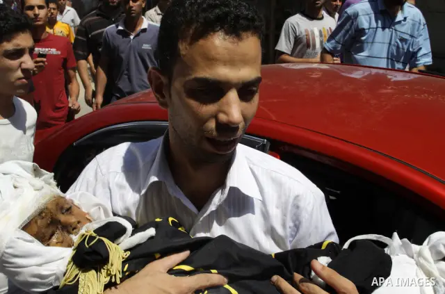 A Palestinian man carries the body of two-year-old boy Islam Qreqa during a funeral in Gaza City on August 20, 2011. Palestinians said at least nine militants have died in multiple Israeli strikes, as well as two childre...