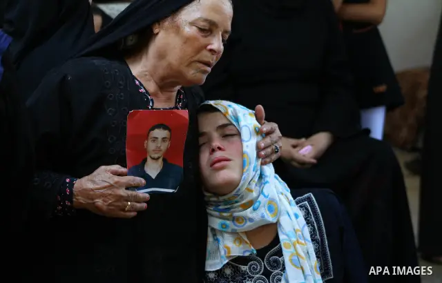 The sister of Palestinian Islamic Jihad militant Anwar Isleem (seens on the photograph) and her mother mourn during his funeral in Bureij Refugee Camp in central Gaza Strip on August 20, 2011. Anwar Isleem and Emad Abu A...