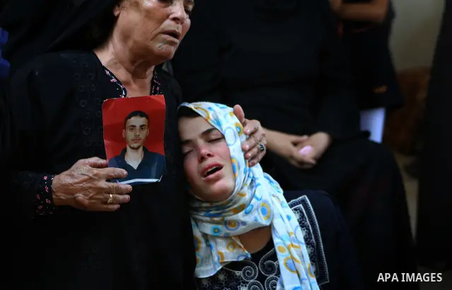 The sister of Palestinian Islamic Jihad militant Anwar Isleem (seens on the photograph) mourns during his funeral in Bureij Refugee Camp in central Gaza Strip on 20 August 2011. Anwar Isleem and Emad Abu Aabdeh were kill...