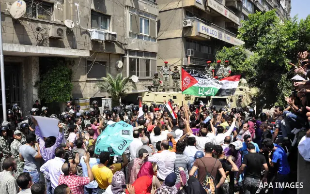 Egyptian military policemen stand guard as demonstrators wave Egyptian and Palestinian (L) flags during a protest outside the Israeli embassy in Cairo on August 20, 2011. Egypt decided to recall its ambassador from Israe...