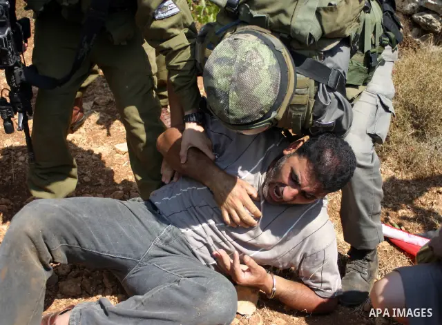 A demonstrator shouts anti-occupation slogans as Israeli soldiers try to detain him during a demonstration by locals, left-wing Israelis, foreigner peace activists in Beit Omar, near the West Bank city of Hebron on Augus...