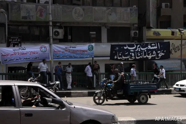Egyptians pass under an Arabic banner with the phrase "People demand to expel the Israeli ambassador" near the Israeli embassy in Cairo, Egypt, Sunday, Aug. 21, 2011. Hundreds of Egyptians protest the deaths of Egyptian...