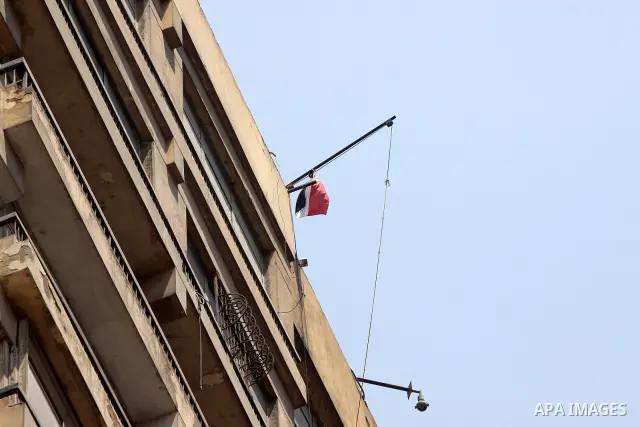 An Egyptian flag with the words "Egypt's Revolution, the 25th of January" flies over the Israeli embassy after a protester managed, at dawn, to climb 15 floors on a building where the Israeli embassy is located to remove...