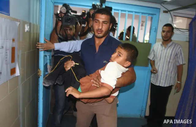 A Palestinian man carries a wounded youth into a hospital following an Israeli attack on Gaza City on August 21, 2011. Photo by Ashraf Amra