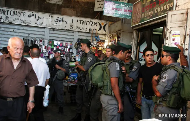 Palestinian Muslims walk past Israeli soldiers at a barricade near the Damascus Gate in East Jerusalem as Israel restricts attendance at the al-Aqsa Mosque in Jerusalem's Old City on August 21,2011.. Photo by Mahfouz Abu...