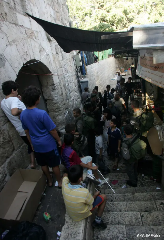 Palestinian Muslims walk past Israeli soldiers at a barricade near the Damascus Gate in East Jerusalem as Israel restricts attendance at the al-Aqsa Mosque in Jerusalem's Old City on August 21,2011.. Photo by Mahfouz Abu...