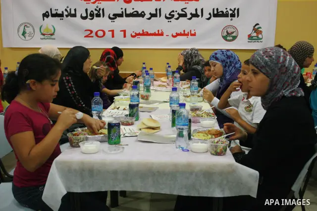 Palestinians take part in the Central Ramadan breakfast for the first orphanage, organized by the United Arab Emirates State charity , in the West Bank city of Nablus, monday Aug . 22,2011. Muslims throughout the world a...
