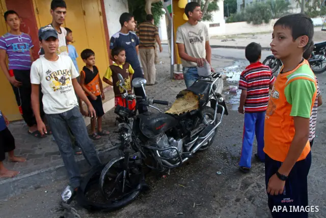 Palestinians inspect a motorcycle damaged in an Israeli air strike in Deir al-Balah in the central Gaza Strip on August 24, 2011. An Israeli strike killed Ismael al-Ismar, 34, in Rafah scarcely 48 hours after militant fa...