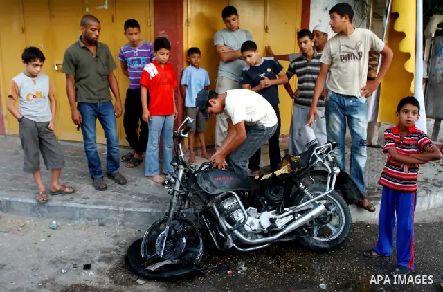 Palestinians inspect a motorcycle damaged in an Israeli air strike in Deir al-Balah in the central Gaza Strip on August 24, 2011. An Israeli strike killed Ismael al-Ismar, 34, in Rafah scarcely 48 hours after militant fa...