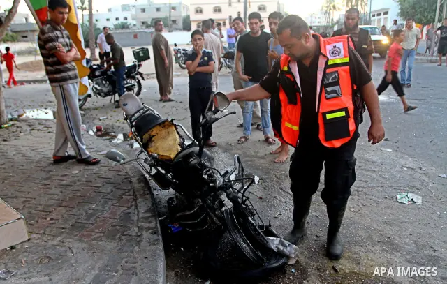Palestinians inspect a motorcycle damaged in an Israeli air strike in Deir al-Balah in the central Gaza Strip on August 24, 2011. An Israeli strike killed Ismael al-Ismar, 34, in Rafah scarcely 48 hours after militant fa...