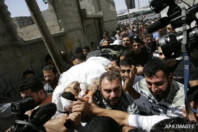 Palestinian mourners carry the body of Islamic Jihad militant Ismael Al-Asmar during his funeral after an Israeli air strike hit his car in Rafah in the southern Gaza Strip on 24 August 2011. Al-Asmar, one of the militan...