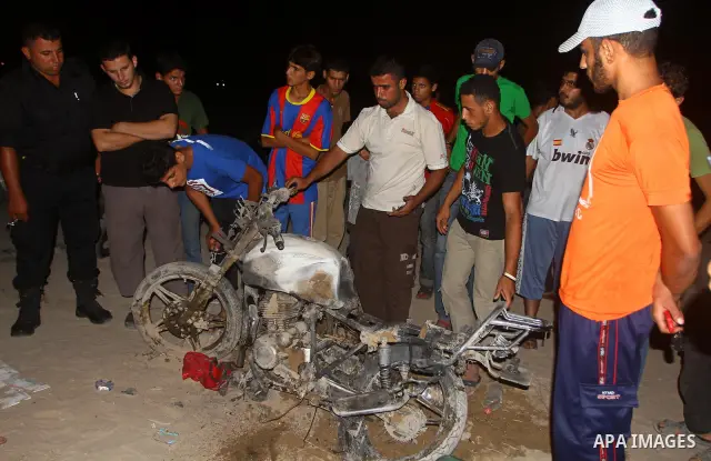 Palestinians gather around a destroyed motorcycle following an Israeli air strike killing two Islamic Jihad militants, at the main road in Jabaliya, northern Gaza Strip, Thursday, Aug. 25, 2011. Palestinian official said...