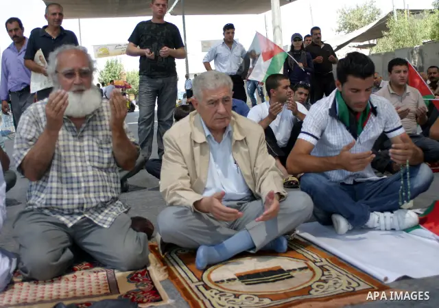 Arabic Muslim worshipers prevented from entering the Al-Aqsa Mosque pray outside an Israeli checkpoint on the outskirts of the West Bank city of Bethlehem on August 26, 2011 as they wait to cross into Jerusalem to attend...