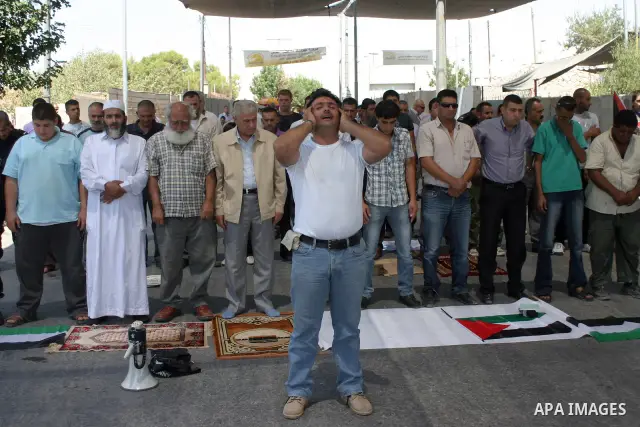 Arabic Muslim worshipers prevented from entering the Al-Aqsa Mosque pray outside an Israeli checkpoint on the outskirts of the West Bank city of Bethlehem on August 26, 2011 as they wait to cross into Jerusalem to attend...