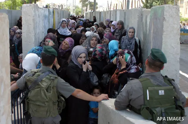 Palestinian women wait to pass the checkpoint on their way to pray at the Al Aqsa Mosque, on the last Friday of the Muslim holy month of Ramadan, in the West Bank town of Bethlehem, early Friday, Aug. 26, 2011. Muslims a...