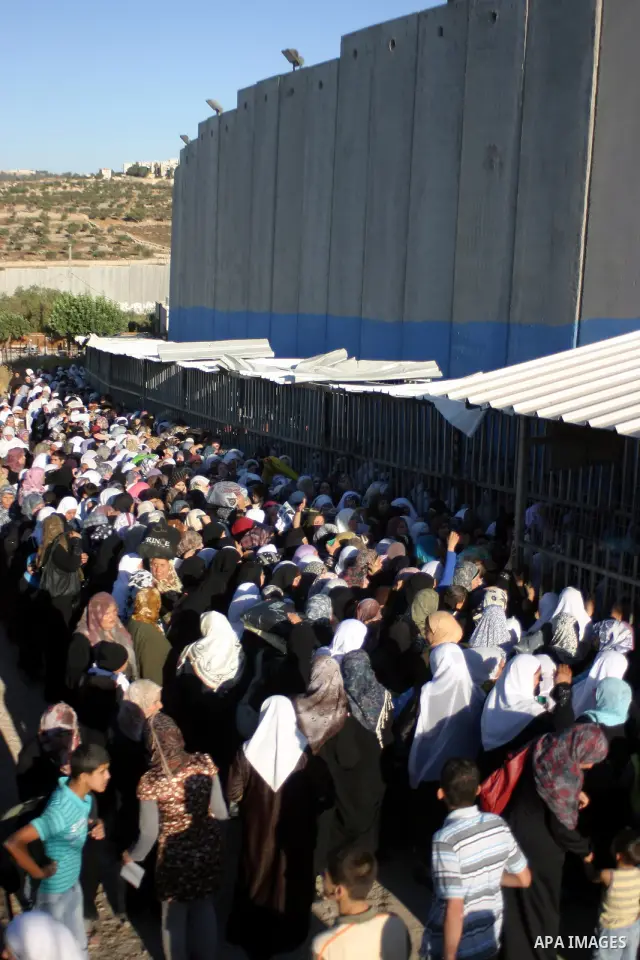 Palestinian women wait to pass the checkpoint on their way to pray at the Al Aqsa Mosque, on the last Friday of the Muslim holy month of Ramadan, in the West Bank town of Bethlehem, early Friday, Aug. 26, 2011. Muslims a...