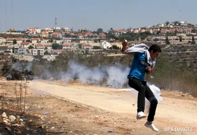 Palestinians run to seek cover from tear gas in clashes with Israeli troops during the weekly protest against the settlement of Qadomim, near the village of Kofr Qadom, west of Nablus City, in the Israeli-occupied West B...
