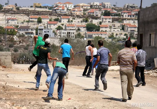 Palestinians throw stones toward Israeli troops during the weekly protest against the settlement of Qadomim, near the village of Kofr Qadom, west of Nablus City, in the Israeli-occupied West Bank on 26 August 2011. Repor...