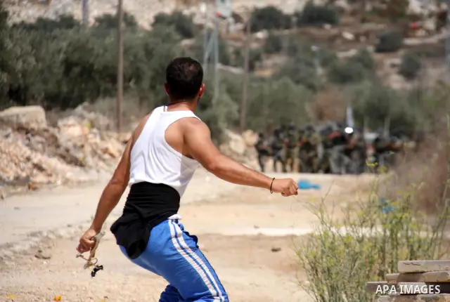 Palestinians throw stones toward Israeli troops during the weekly protest against the settlement of Qadomim, near the village of Kofr Qadom, west of Nablus City, in the Israeli-occupied West Bank on 26 August 2011. Repor...