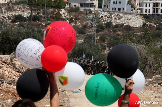 Palestinians wave with colored balloons in front of Israeli troops during the weekly protest against the settlement of Qadomim, near the village of Kofr Qadom, west of Nablus City, in the Israeli-occupied West Bank on 26...