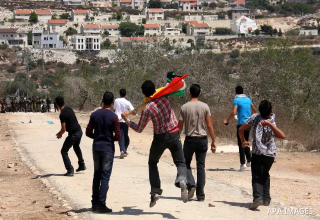 Palestinians throw stones toward Israeli troops during the weekly protest against the settlement of Qadomim, near the village of Kofr Qadom, west of Nablus City, in the Israeli-occupied West Bank on 26 August 2011. Repor...
