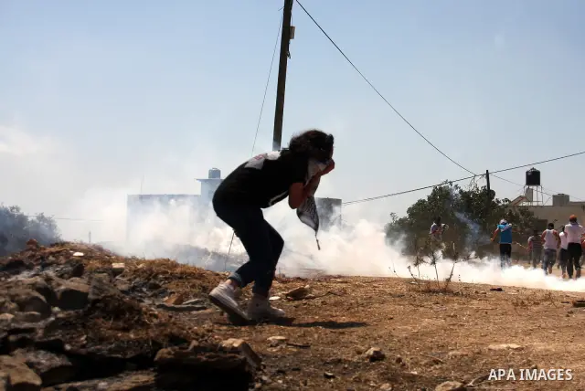Palestinians run to seek cover from tear gas in clashes with Israeli troops during the weekly protest against the settlement of Qadomim, near the village of Kofr Qadom, west of Nablus City, in the Israeli-occupied West B...