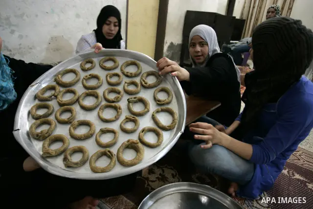 Palestinian women prepare date-filled mini cakes traditional for the Eid al-Fitr, a three-day holiday that marks the end of the fasting month of Ramadan,In their home in Rafah, southern Gaza Strip on Aug. 28, 2011. Photo...
