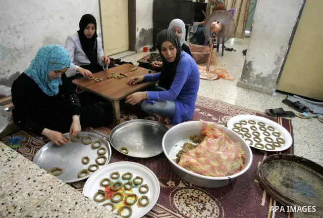 Palestinian women prepare date-filled mini cakes traditional for the Eid al-Fitr, a three-day holiday that marks the end of the fasting month of Ramadan,In their home in Rafah, southern Gaza Strip on Aug. 28, 2011. Photo...