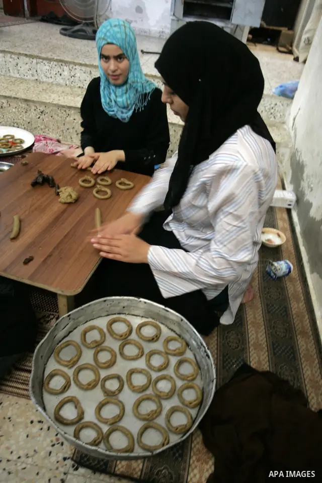 Palestinian women prepare date-filled mini cakes traditional for the Eid al-Fitr, a three-day holiday that marks the end of the fasting month of Ramadan,In their home in Rafah, southern Gaza Strip on Aug. 28, 2011. Photo...