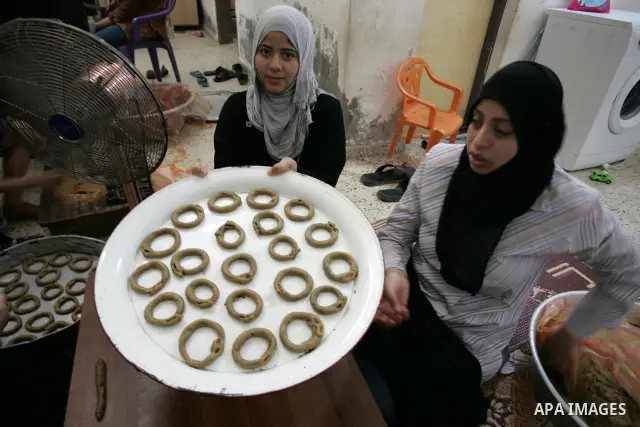 Palestinian women prepare date-filled mini cakes traditional for the Eid al-Fitr, a three-day holiday that marks the end of the fasting month of Ramadan,In their home in Rafah, southern Gaza Strip on Aug. 28, 2011. Photo...