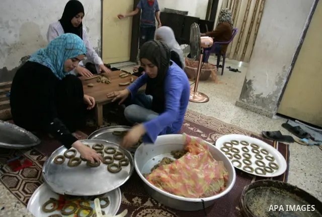 Palestinian women prepare date-filled mini cakes traditional for the Eid al-Fitr, a three-day holiday that marks the end of the fasting month of Ramadan,In their home in Rafah, southern Gaza Strip on Aug. 28, 2011. Photo...