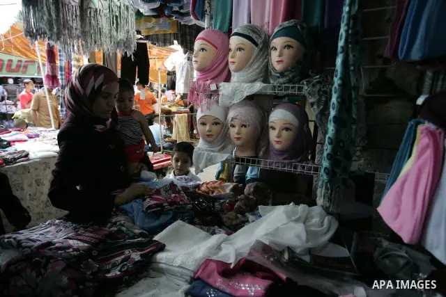 Palestinian women shop at a clothes shop as Muslims shop ahead of the Eid al-Fitr celebrations in Rafah, southern Gaza Strip on Aug. 28, 2011. Muslims in the region will celebrate the Eid al-Fitr holiday starting with th...