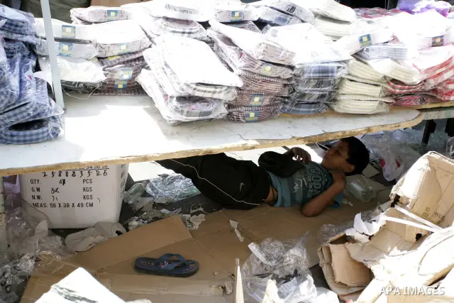 A Palestinian boy sleeps under a clothes at a market as Muslims shop ahead of the Eid al-Fitr celebrations in Rafah, southern Gaza Strip on Aug. 28, 2011. Muslims in the region will celebrate the Eid al-Fitr holiday star...