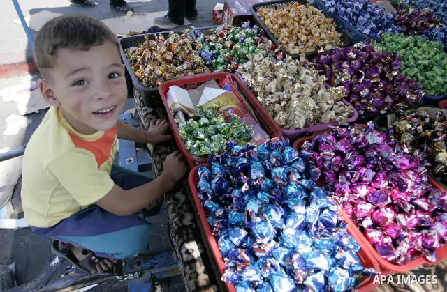 A Palestinian boy sits near sweets as Muslims shop ahead of the Eid al-Fitr celebrations in Rafah, southern Gaza Strip on Aug. 28, 2011. Muslims in the region will celebrate the Eid al-Fitr holiday starting with thewith...