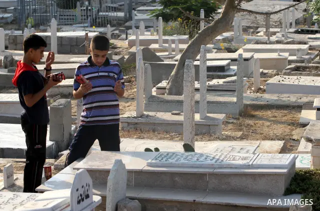 Palestinians visit their relatives' graves in a cemetery during the first day of Eid al-Fitr in Gaza city on August 30, 2011. Eid al-Fitr marks the end of the Muslim holy month of Ramadan. Photo by Mohammed Asad