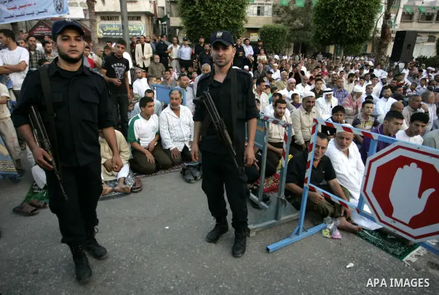 Security forces stand guard as Palestinians attend an open air morning prayer to celebrate Eid al-Fitr in Khan Yunis town the southern Gaza Strip on August 30, 2011. The Palestinian Territories, along with other neighbor...