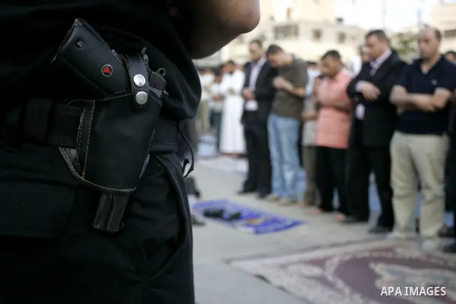 Security forces stand guard as Palestinians attend an open air morning prayer to celebrate Eid al-Fitr in Khan Yunis town the southern Gaza Strip on August 30, 2011. The Palestinian Territories, along with other neighbor...
