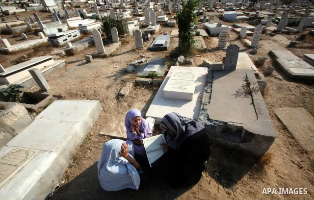 Palestinians visit their relatives' graves in a cemetery during the first day of Eid al-Fitr in the southern Gaza Strip on August 30, 2011. Eid al-Fitr marks the end of the Muslim holy month of Ramadan. Photo by Ali Jada...