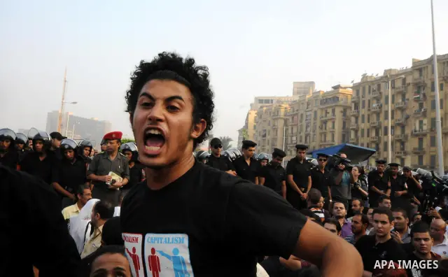 A man shouts slogans as Egyptian Muslims gather to pray, celebrating the start of the three-day feast known in Arabic Eid al-Fitr, which marks the end of the holy fasting month of Ramadan, in Tahrir Square, the scene of...