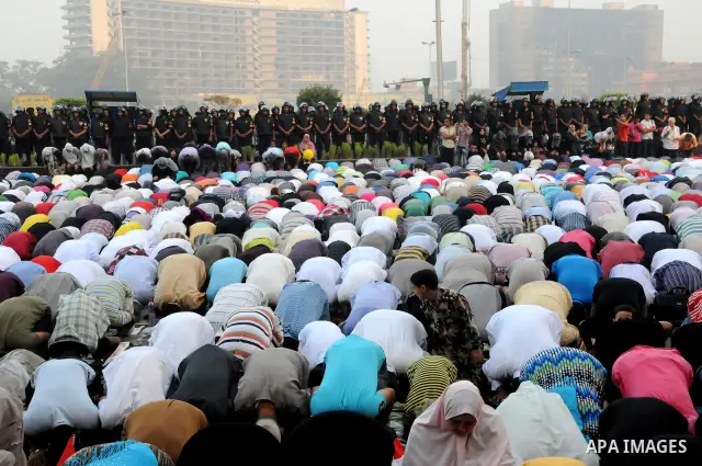 Police and military stand guard as Egyptian Muslims gather to pray, celebrating the start of the three-day feast known in Arabic Eid al-Fitr, which marks the end of the holy fasting month of Ramadan, in Tahrir Square, th...