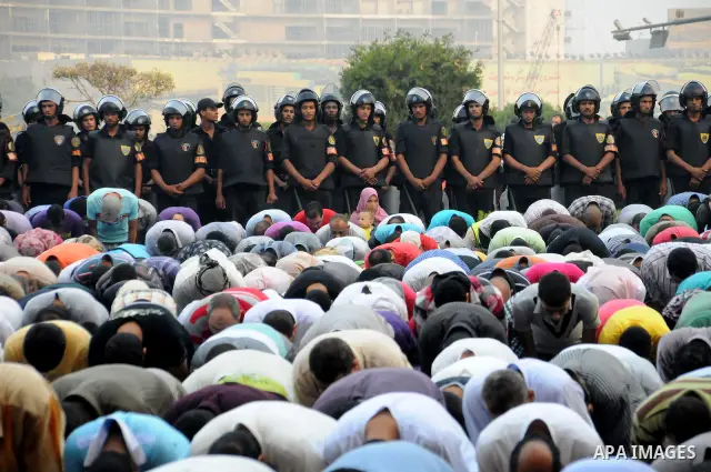 Police and military stand guard as Egyptian Muslims gather to pray, celebrating the start of the three-day feast known in Arabic Eid al-Fitr, which marks the end of the holy fasting month of Ramadan, in Tahrir Square, th...