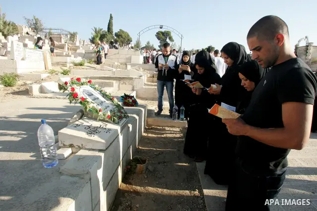 A Palestinian family gather to pray over the graves of loved ones in a cemetery near the Al-Aqsa Mosque compound in Jerusalem's Old City on August 30, 2011, marking the first day of Eid al-Fitr and the end of the holy fa...