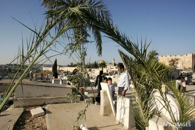 A Palestinian family gather to pray over the graves of loved ones in a cemetery near the Al-Aqsa Mosque compound in Jerusalem's Old City on August 30, 2011, marking the first day of Eid al-Fitr and the end of the holy fa...