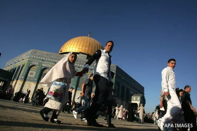 Palestinians walk after performing the morning Eid Al-Fitr prayer in front of the Dome of Rock at the Al-Aqsa Mosque compound, Islam's thrid most holy site, in Israeli annexed East Jerusalem, on August 30, 2011, marking...