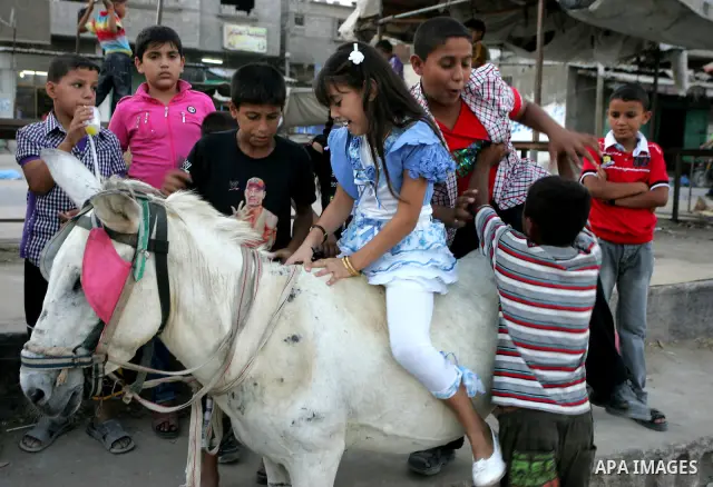 Palestinian children enjoy riding a donkey at the second day of the Eid al-Fitr holiday, which marks the end of the holy fasting month of Ramadan in Rafah in the southern Gaza Strip on August 31 2011. Photo by Abed Rahim...