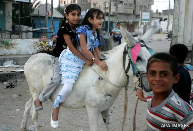 Palestinian children enjoy riding a donkey at the second day of the Eid al-Fitr holiday, which marks the end of the holy fasting month of Ramadan in Rafah in the southern Gaza Strip on August 31 2011. Photo by Abed Rahim...