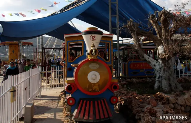 Palestinian children enjoy a ride at an amusement park on the second day of the Eid al-Fitr holiday, which marks the end of the holy fasting month of Ramadan, in the West Bank city of Nablus, 31 August 2011. Photo by Wag...