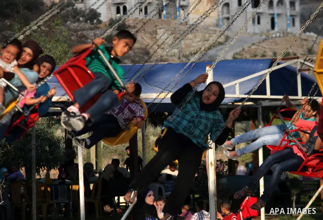Palestinian children enjoy a ride at an amusement park on the second day of the Eid al-Fitr holiday, which marks the end of the holy fasting month of Ramadan, in the West Bank city of Nablus, 31 August 2011. Photo by Wag...