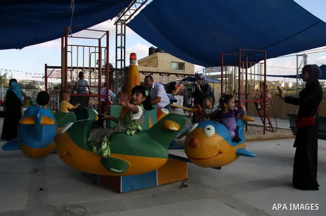 Palestinian children enjoy a ride at an amusement park on the second day of the Eid al-Fitr holiday, which marks the end of the holy fasting month of Ramadan, in the West Bank city of Nablus, 31 August 2011. Photo by Wag...