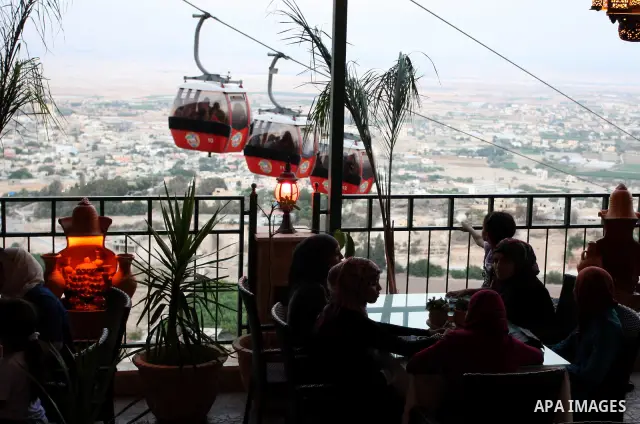 Tourists tour the historic sites of Jericho in cable cars during celebrations on the third day of the Eid al-Fitr holiday, which marks the end of the holy fasting month of Ramadan in the West Bank city of Jericho on Sept...